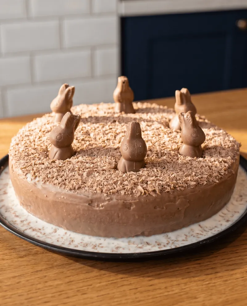 Pastel entero de chocolate decorado con conejitos y hojuelas de chocolate