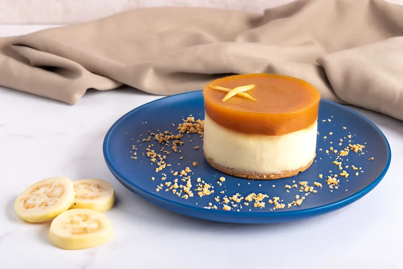 Chocoflan individual de Boston Bakery en plato azul sobre superficie de mármol con tela beige