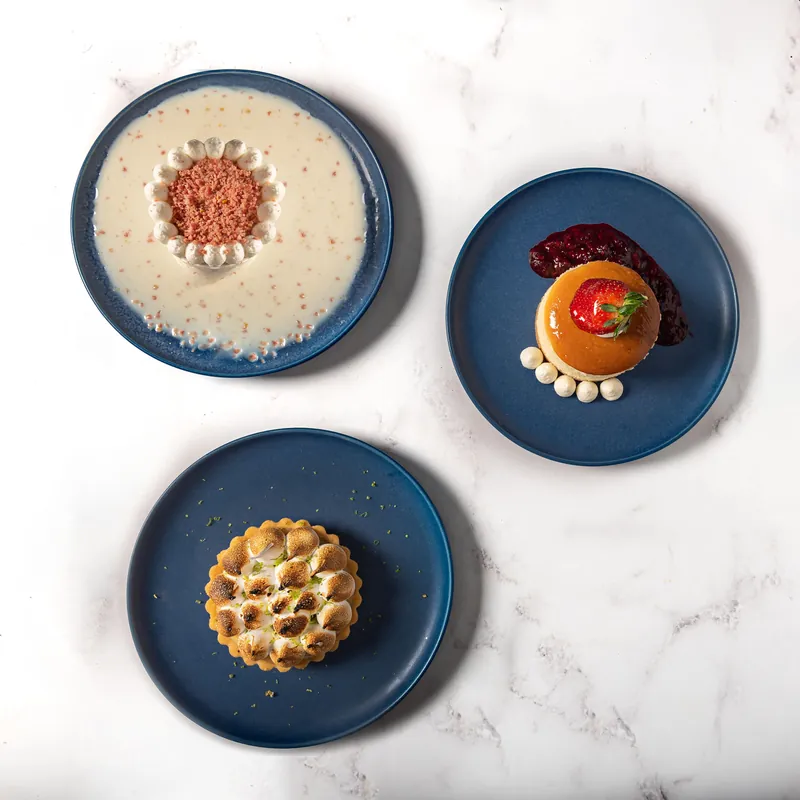 Tres postres individuales de Boston Bakery vistos desde arriba en platos azules sobre mármol
