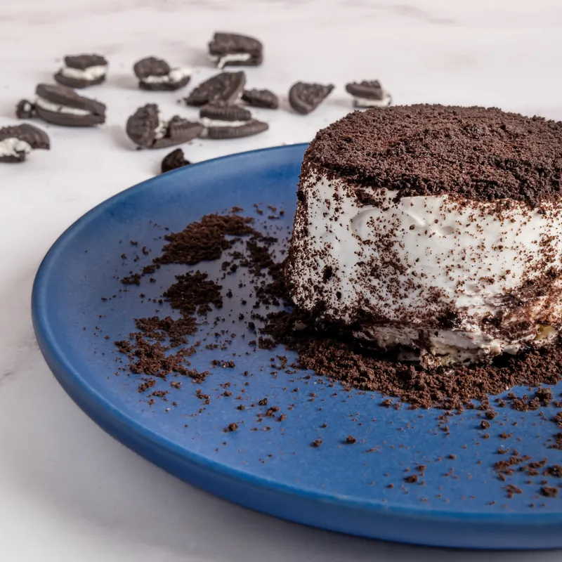 Cheesecake individual de galleta de chocolate cubierto con migas sobre plato azul