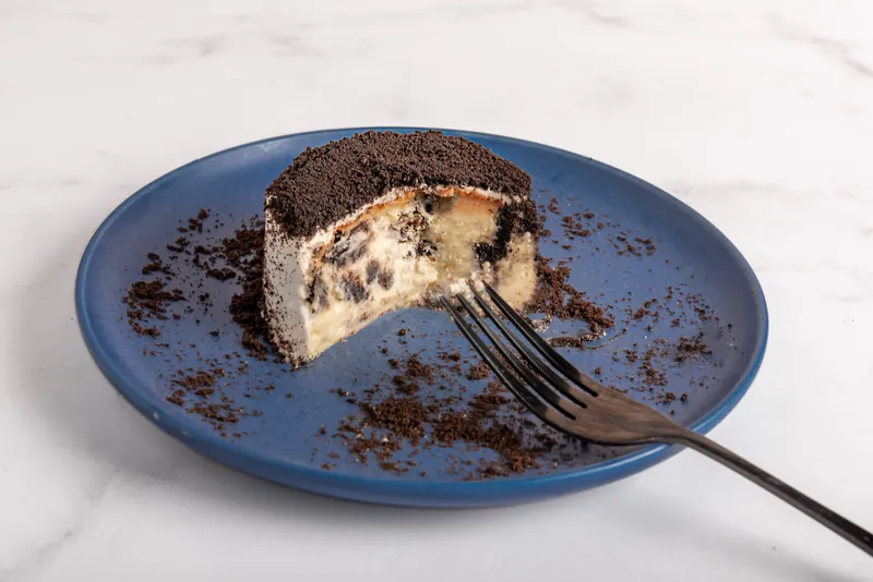 Cheesecake individual de galleta de chocolate con tenedor sobre plato azul de Boston Bakery