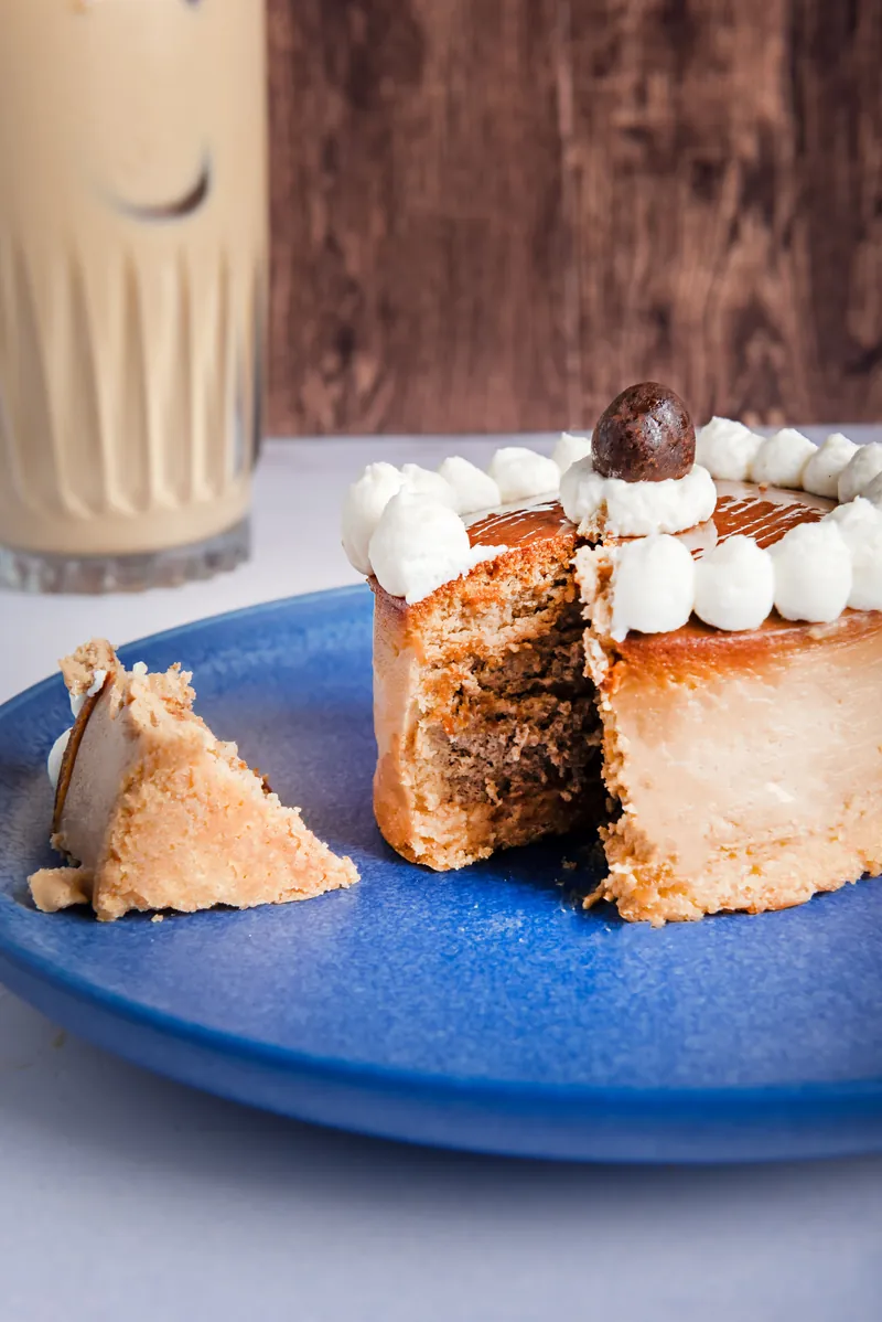 Pastel individual cortado con capas de crema y malvavisco junto a una bebida fría
