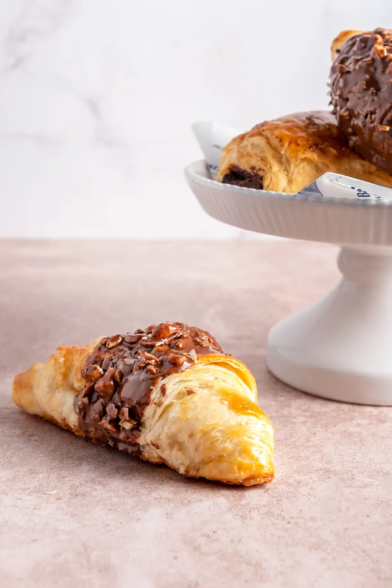 Croissants con chocolate y avellana sobre pedestal blanco en Boston Bakery