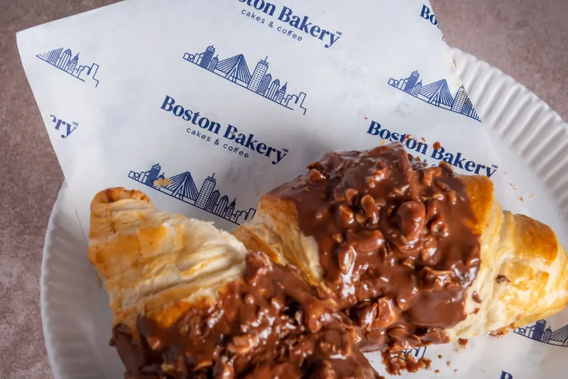 Croissant relleno de chocolate servido sobre papel con la marca Boston Bakery