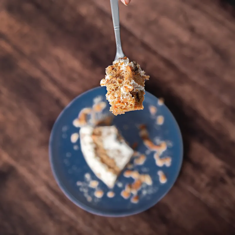 Cucharada de pastel de zanahoria con relleno de queso crema sobre plato azul